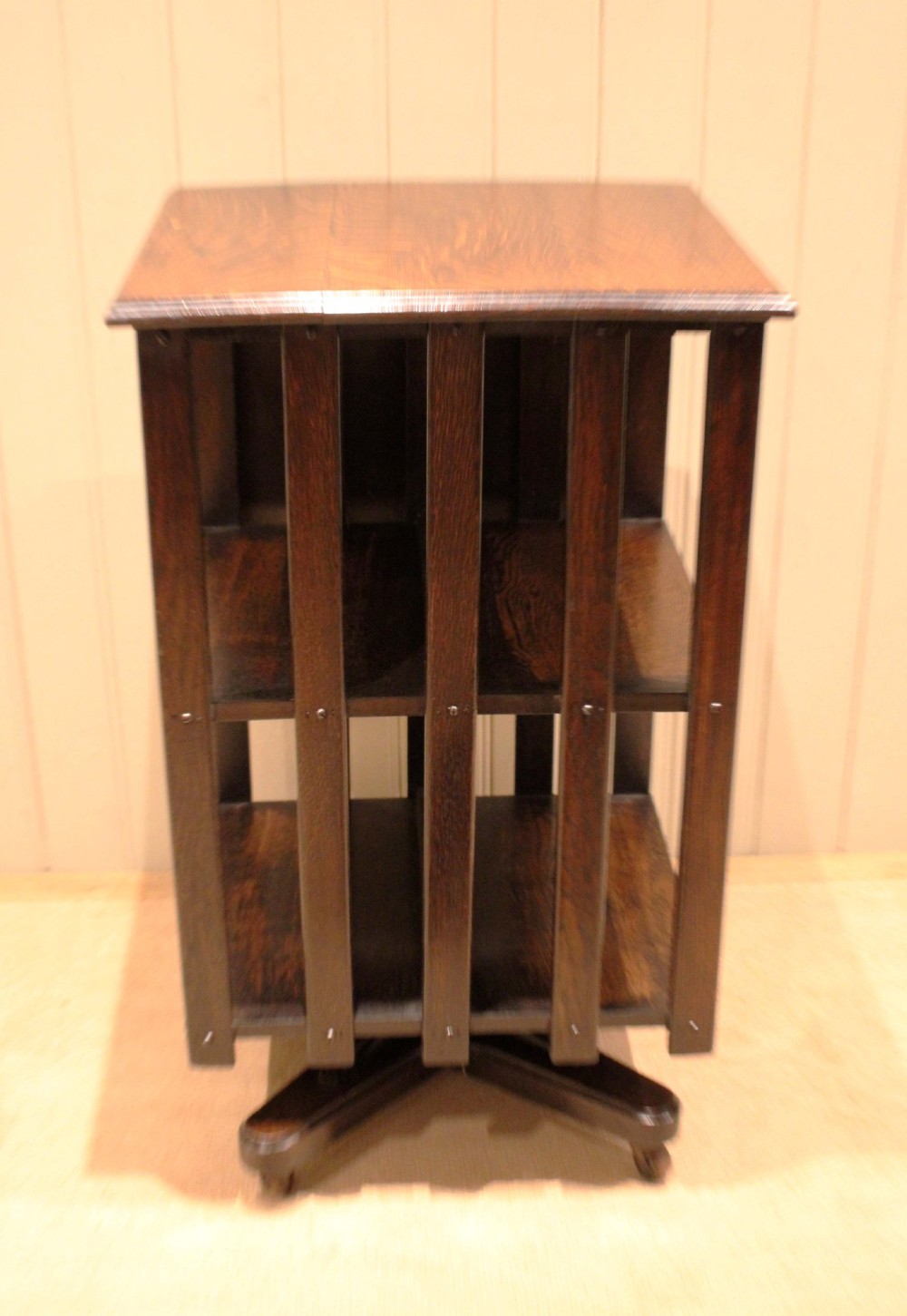 A dark oak revolving bookcase featuring vertical slatted sides, an adjustable reading lectern, and a four-point base on castors. View VI