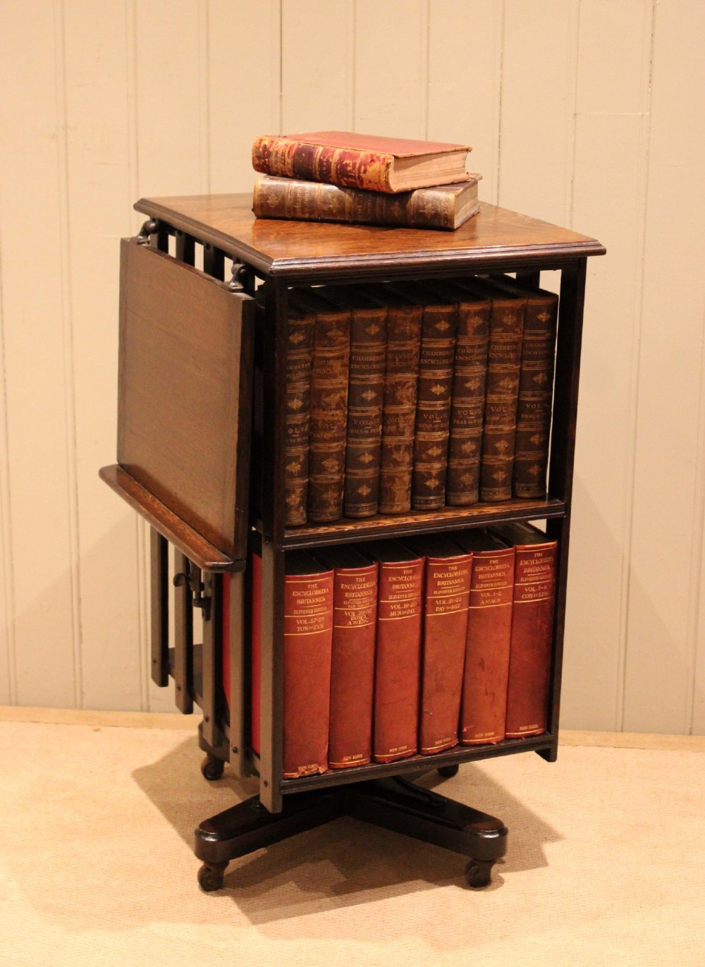 A dark oak revolving bookcase featuring vertical slatted sides, an adjustable reading lectern, and a four-point base on castors. View VII