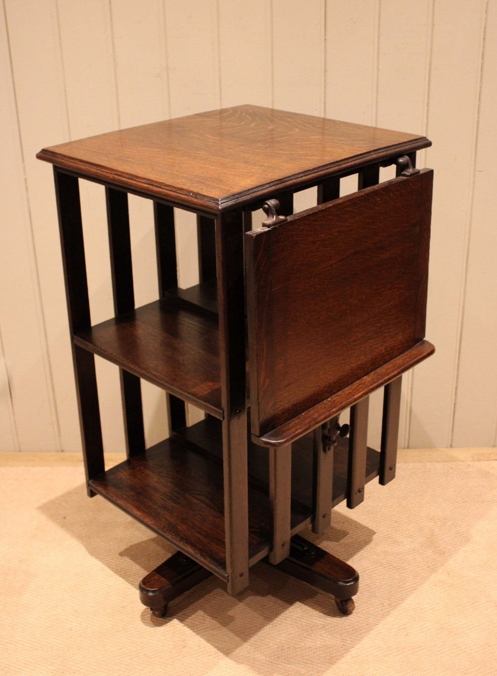 A dark oak revolving bookcase featuring vertical slatted sides, an adjustable reading lectern, and a four-point base on castors. View VIII