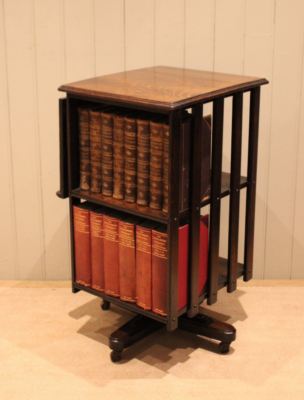A dark oak revolving bookcase featuring vertical slatted sides, an adjustable reading lectern, and a four-point base on castors. View IX