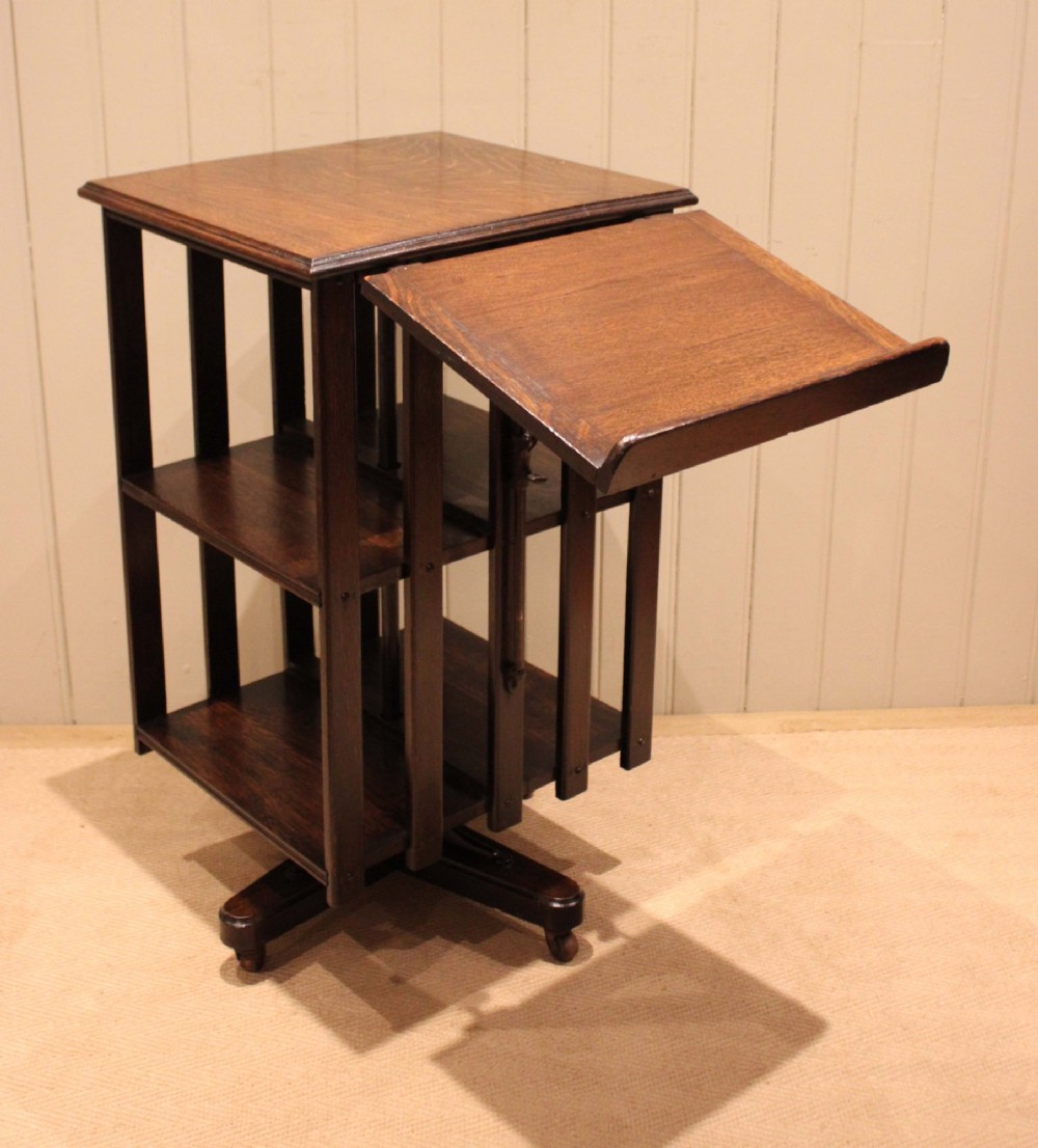 A dark oak revolving bookcase featuring vertical slatted sides, an adjustable reading lectern, and a four-point base on castors. View X