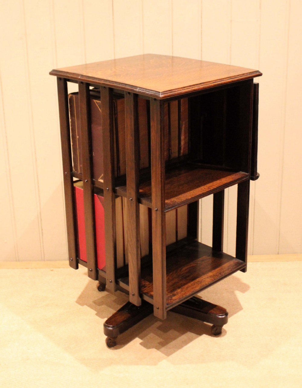 A dark oak revolving bookcase featuring vertical slatted sides, an adjustable reading lectern, and a four-point base on castors. View XI