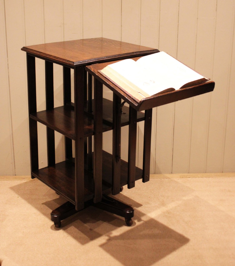 A dark oak revolving bookcase featuring vertical slatted sides, an adjustable reading lectern, and a four-point base on castors. View XII