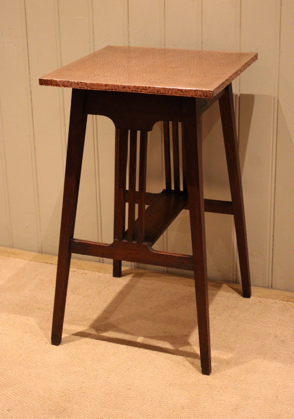 A square Arts and Crafts side table made of dark oak with a hand-hammered copper top, tapered legs, vertical slats, and cross stretchers. View IV