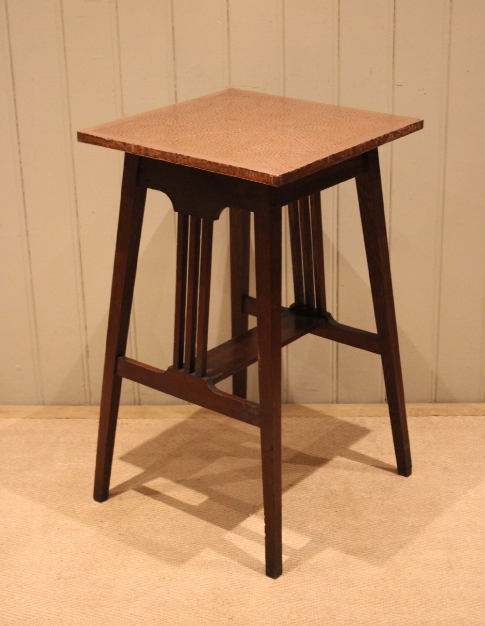 A square Arts and Crafts side table made of dark oak with a hand-hammered copper top, tapered legs, vertical slats, and cross stretchers. View X