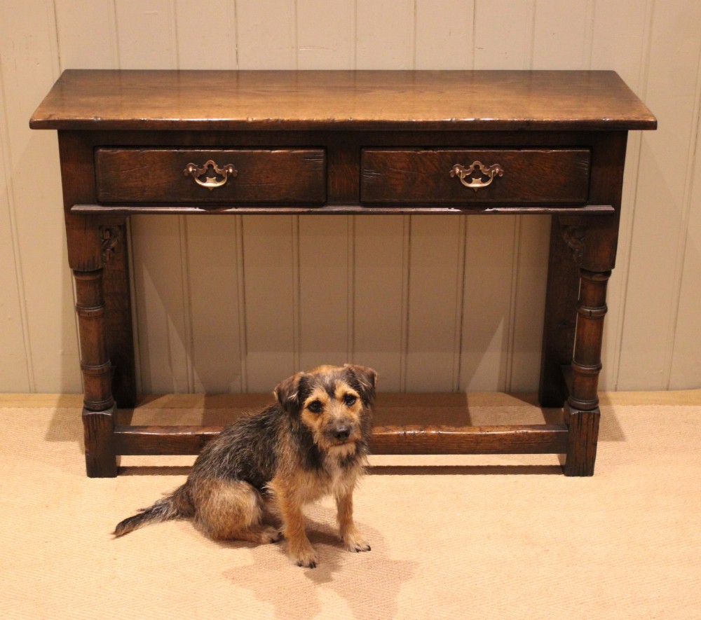 A solid oak server table featuring a rectangular top, two drawers with brass swan-neck handles, turned front legs, and a lower stretcher base. View VIII