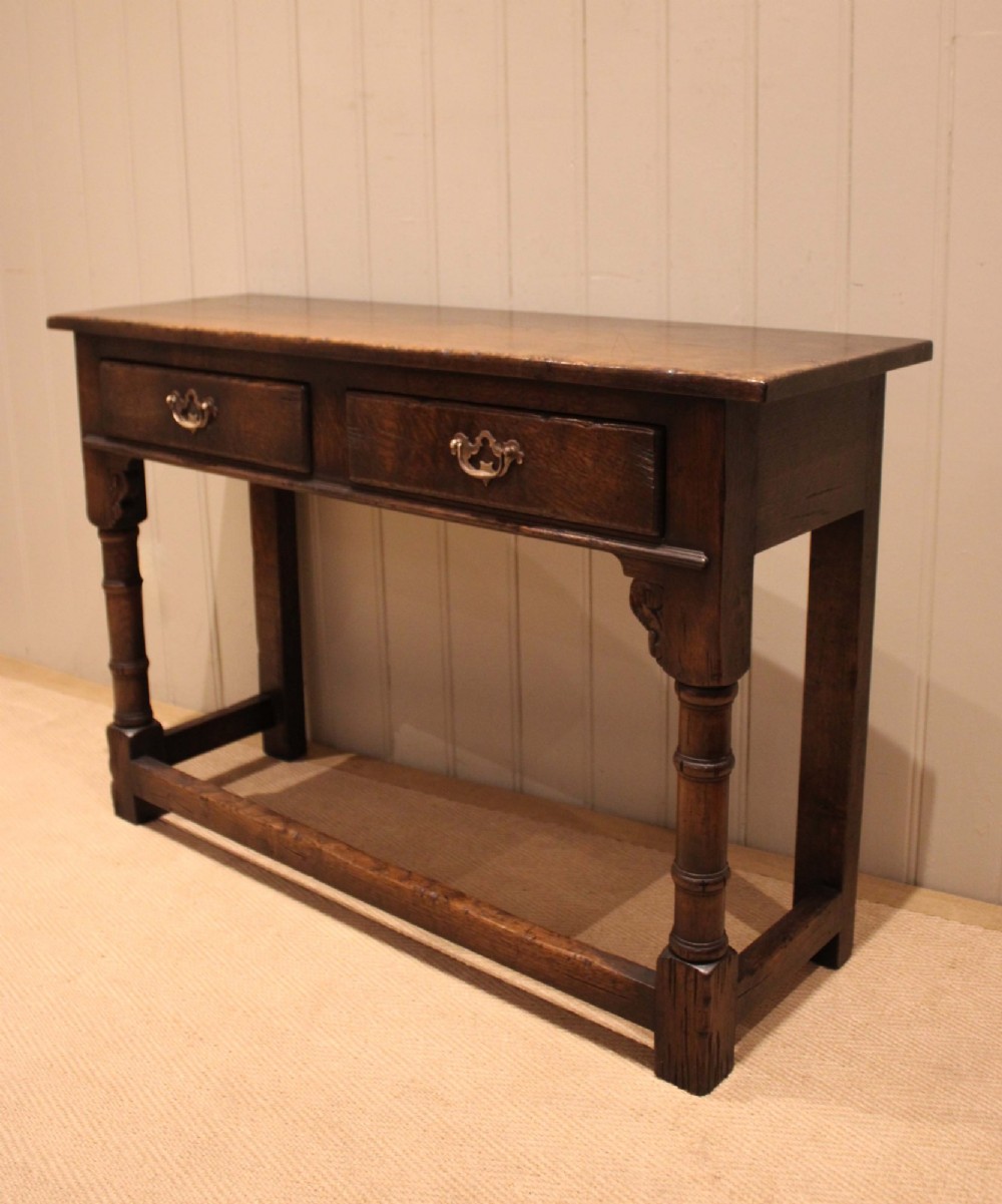 A solid oak server table featuring a rectangular top, two drawers with brass swan-neck handles, turned front legs, and a lower stretcher base. View IX