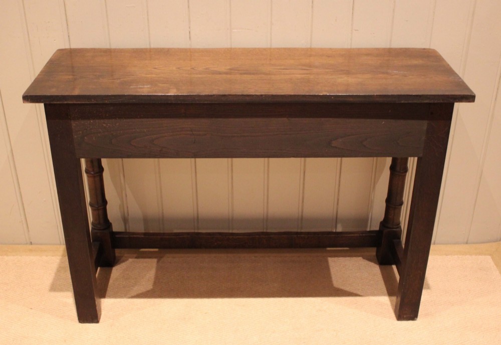 A solid oak server table featuring a rectangular top, two drawers with brass swan-neck handles, turned front legs, and a lower stretcher base. View XI