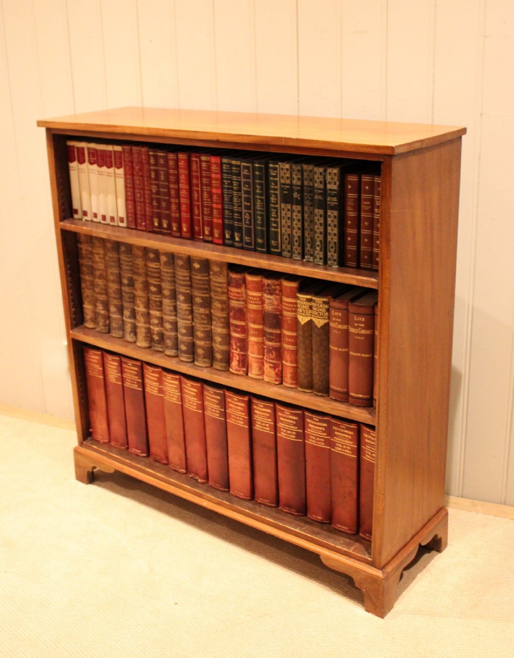 A late nineteenth-century mahogany open bookcase featuring three wide horizontal shelves and bracket feet. View IX