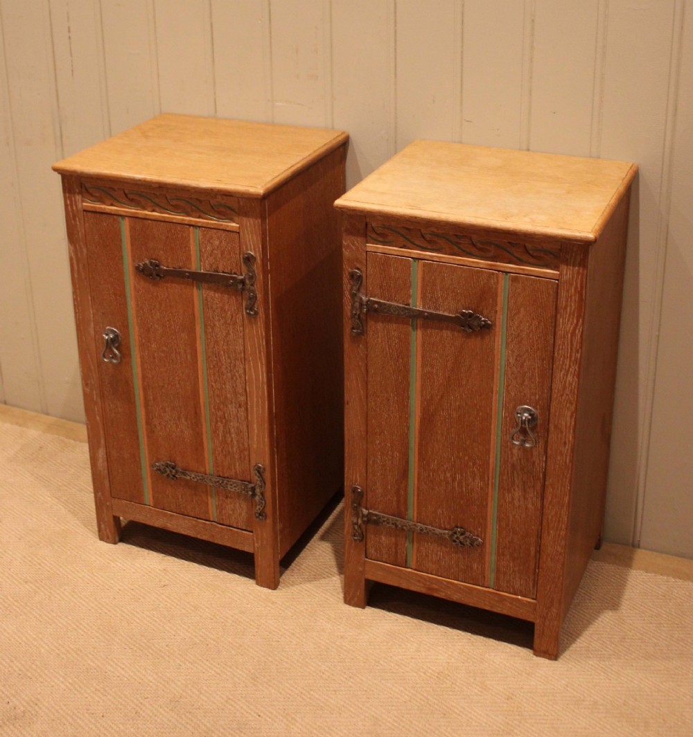 A pair of limed oak bedside cabinets featuring panelled single doors, wrought iron strap hinges, and subtle green painted accents. View II