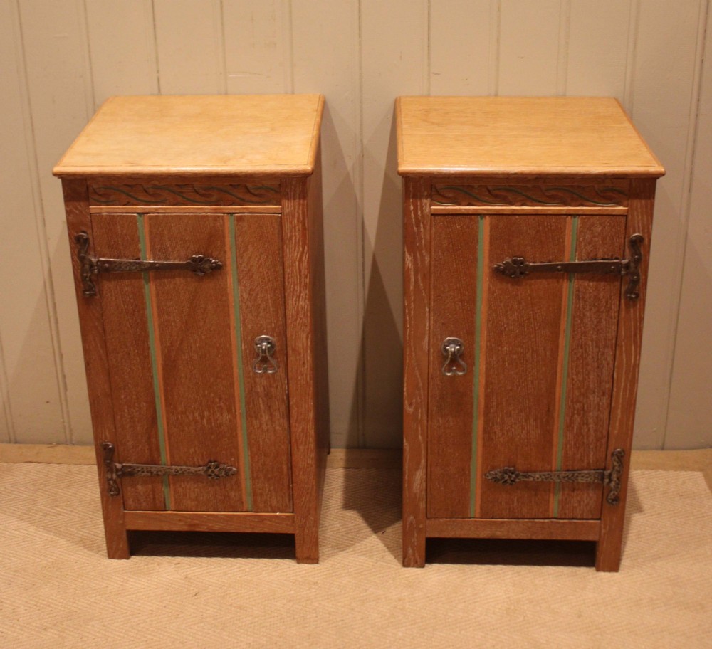 A pair of limed oak bedside cabinets featuring panelled single doors, wrought iron strap hinges, and subtle green painted accents. View III