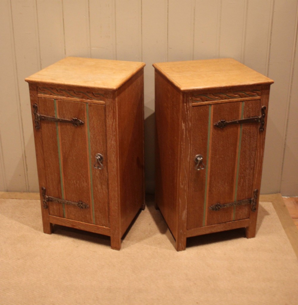 A pair of limed oak bedside cabinets featuring panelled single doors, wrought iron strap hinges, and subtle green painted accents. View IV