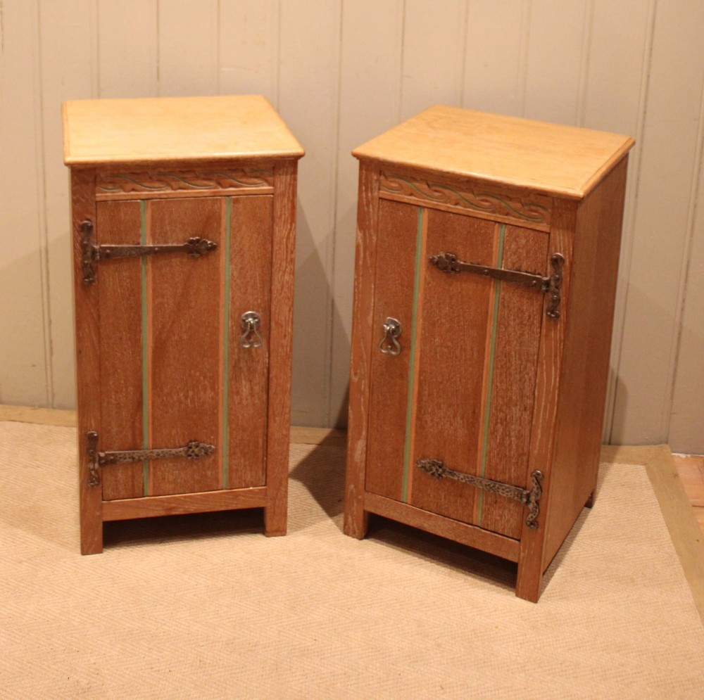 A pair of limed oak bedside cabinets featuring panelled single doors, wrought iron strap hinges, and subtle green painted accents. View V