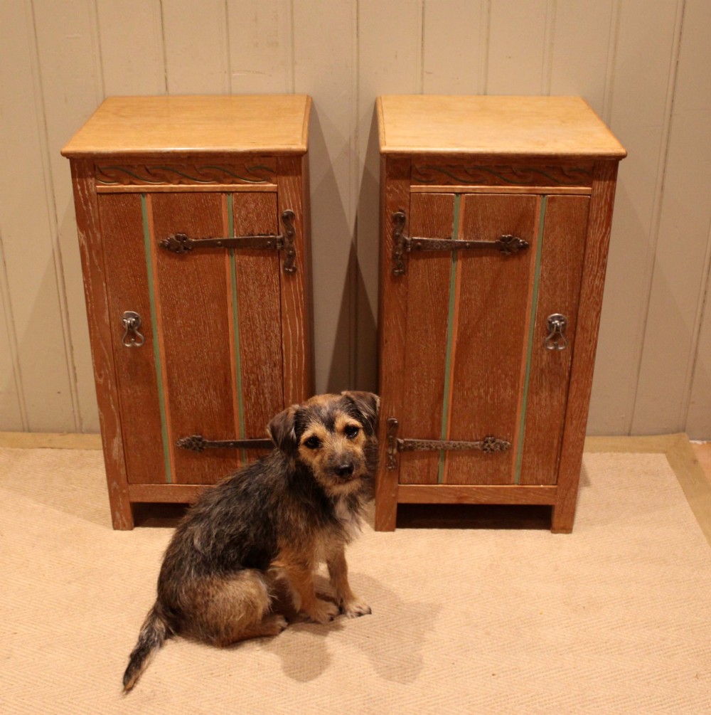 A pair of limed oak bedside cabinets featuring panelled single doors, wrought iron strap hinges, and subtle green painted accents. View VI