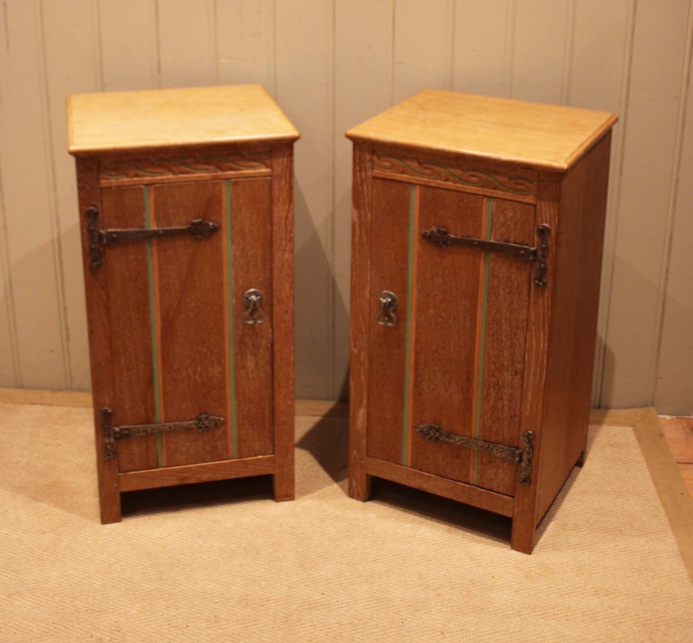 A pair of limed oak bedside cabinets featuring panelled single doors, wrought iron strap hinges, and subtle green painted accents. View VII