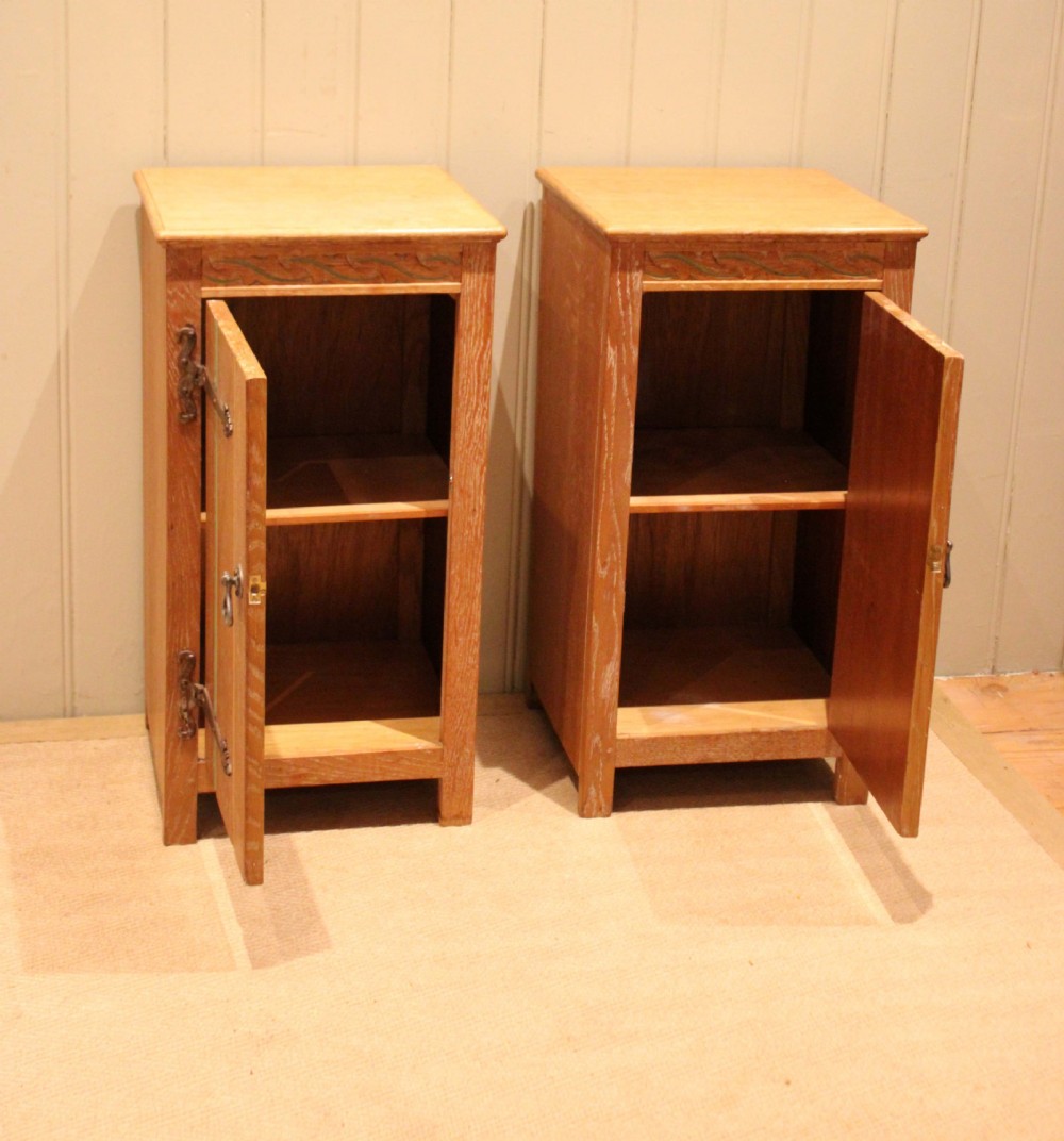 A pair of limed oak bedside cabinets featuring panelled single doors, wrought iron strap hinges, and subtle green painted accents. View VIII