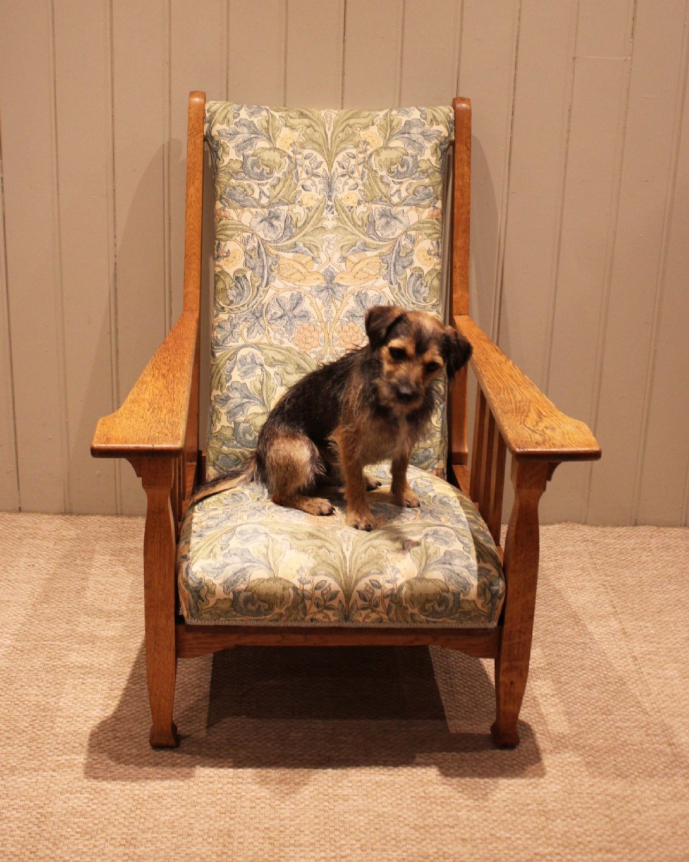 A solid oak Arts and Crafts style armchair featuring broad flat armrests and upholstery decorated with a botanical foliage pattern. View IX