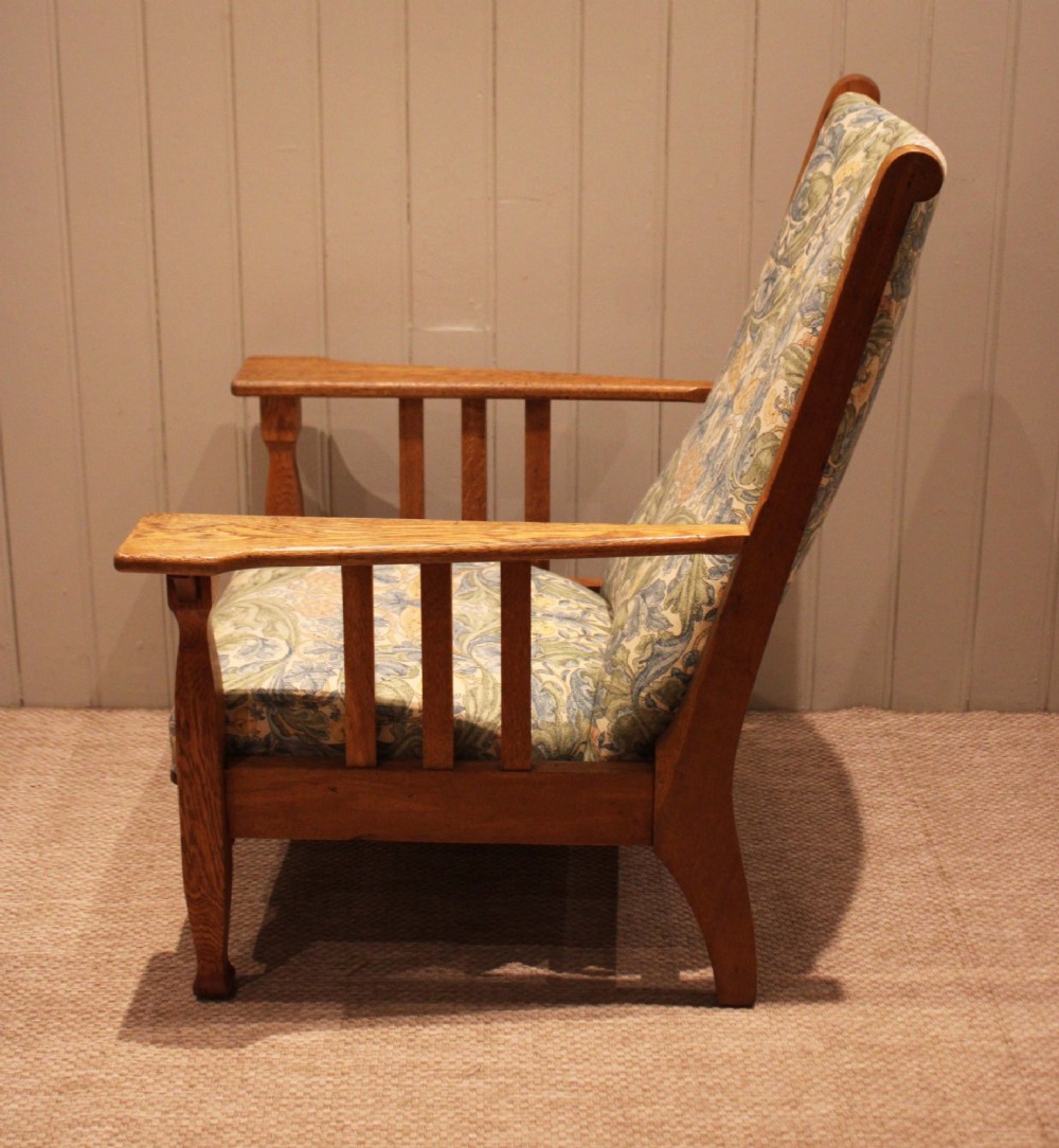 A solid oak Arts and Crafts style armchair featuring broad flat armrests and upholstery decorated with a botanical foliage pattern. View XI