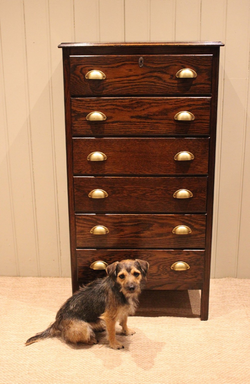 A tall dark oak chest with six stacked drawers and brass cup handles. View X