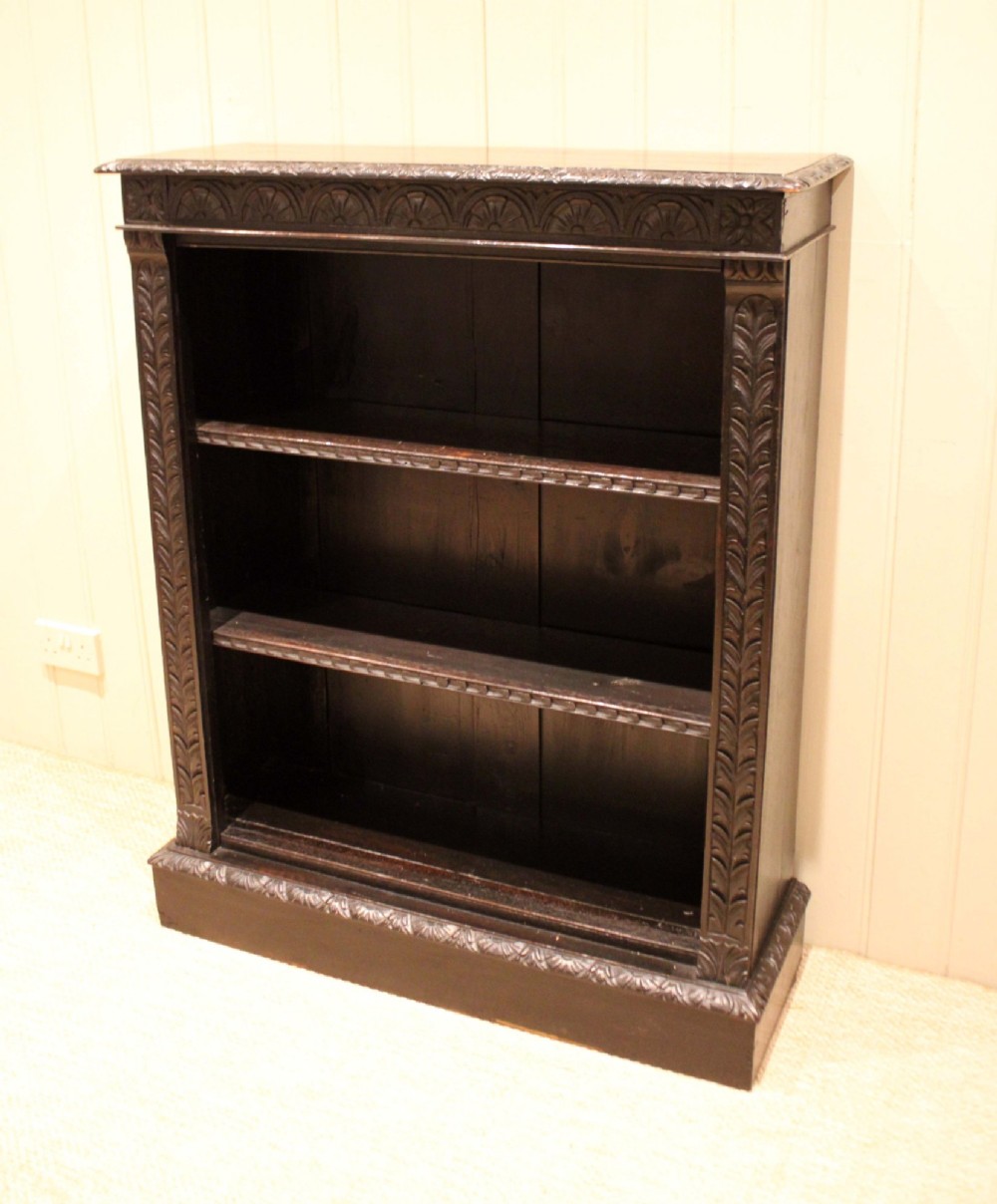 A mid-Victorian dark oak open bookcase featuring hand-carved leaf mouldings and three open shelves filled with antique books. View IV