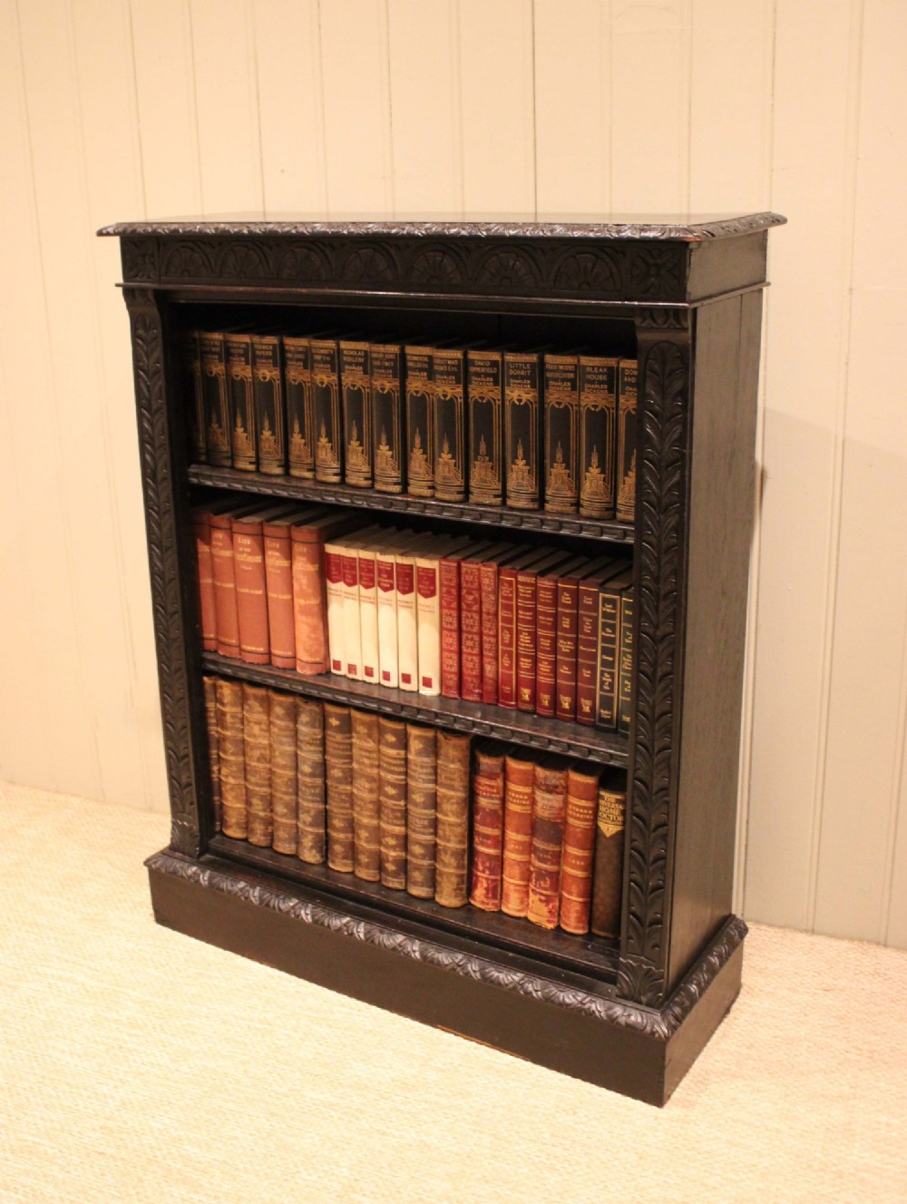 A mid-Victorian dark oak open bookcase featuring hand-carved leaf mouldings and three open shelves filled with antique books. View VII