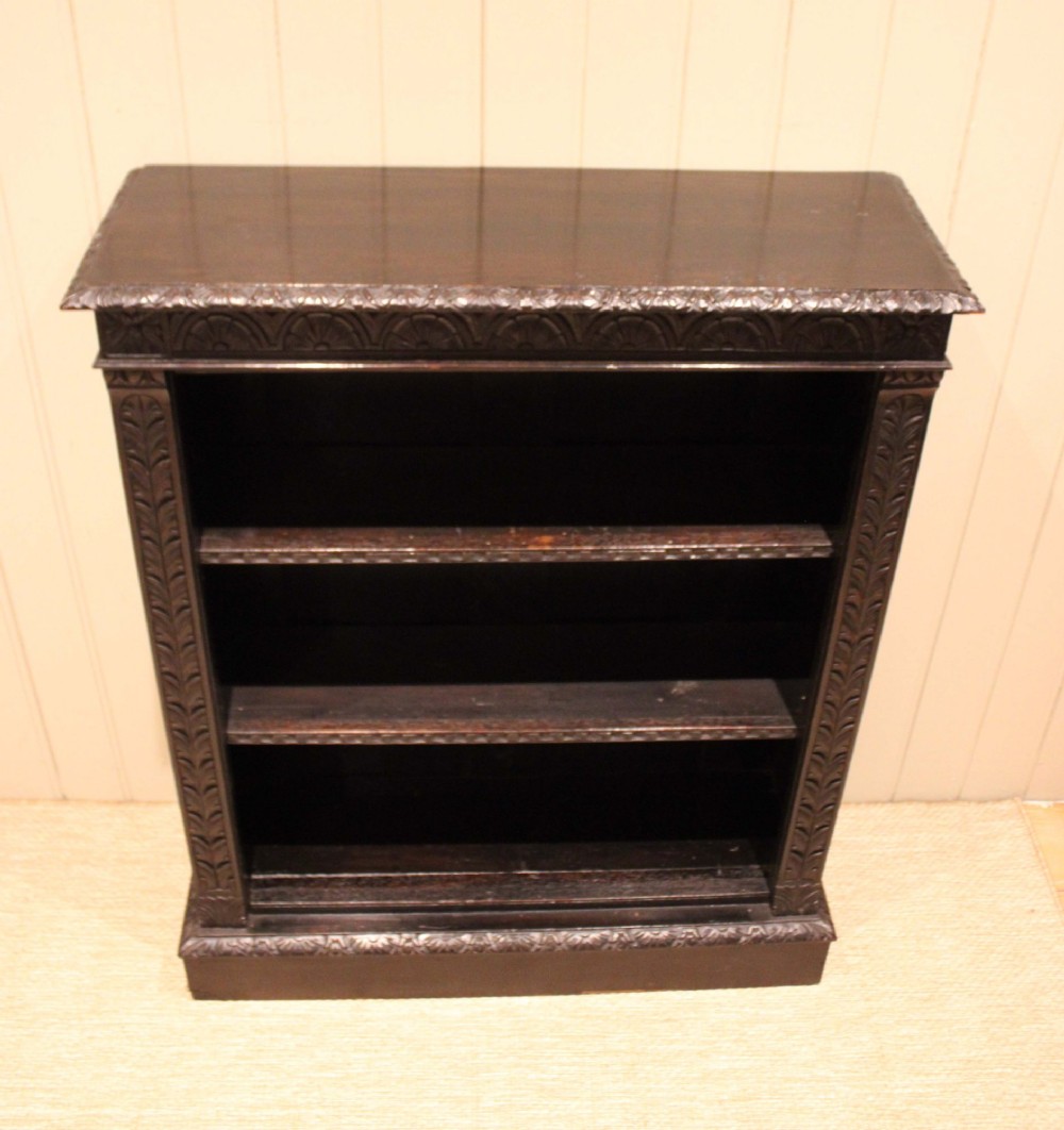A mid-Victorian dark oak open bookcase featuring hand-carved leaf mouldings and three open shelves filled with antique books. View VIII