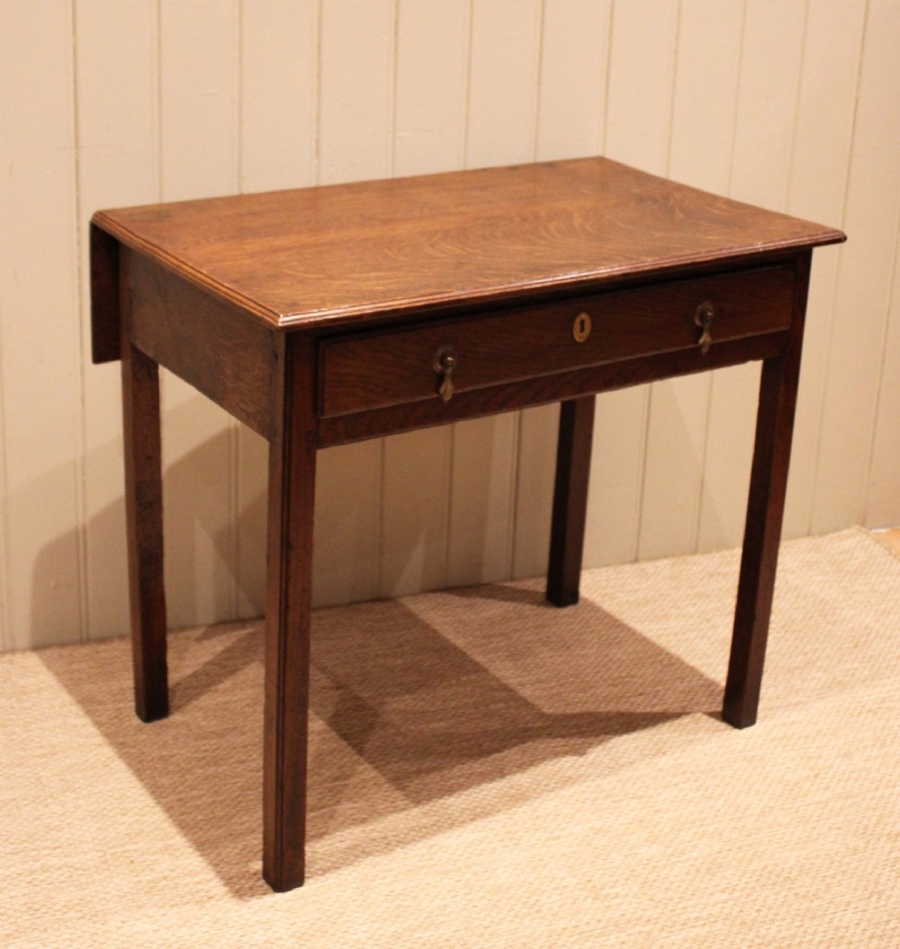 A George III oak side table with a frieze drawer, brass drop handles, a keyhole escutcheon, and straight square legs. View III
