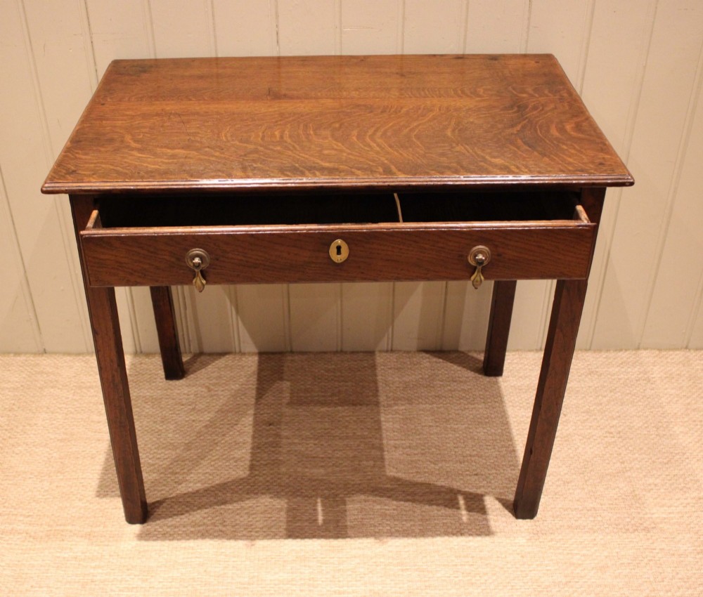 A George III oak side table with a frieze drawer, brass drop handles, a keyhole escutcheon, and straight square legs. View V
