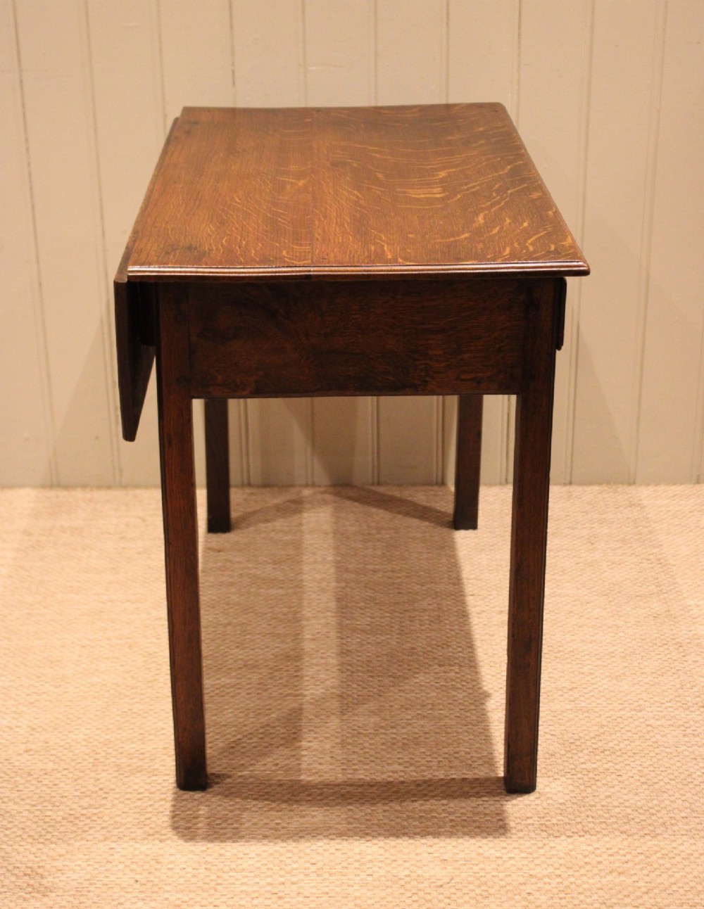 A George III oak side table with a frieze drawer, brass drop handles, a keyhole escutcheon, and straight square legs. View VI