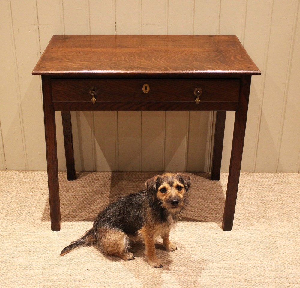 A George III oak side table with a frieze drawer, brass drop handles, a keyhole escutcheon, and straight square legs. View VII