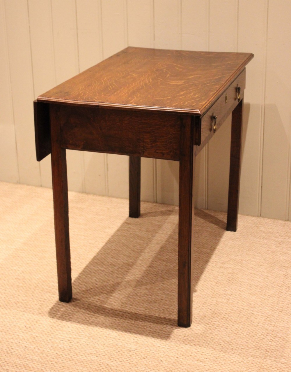 A George III oak side table with a frieze drawer, brass drop handles, a keyhole escutcheon, and straight square legs. View IX