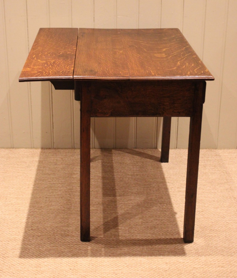 A George III oak side table with a frieze drawer, brass drop handles, a keyhole escutcheon, and straight square legs. View X
