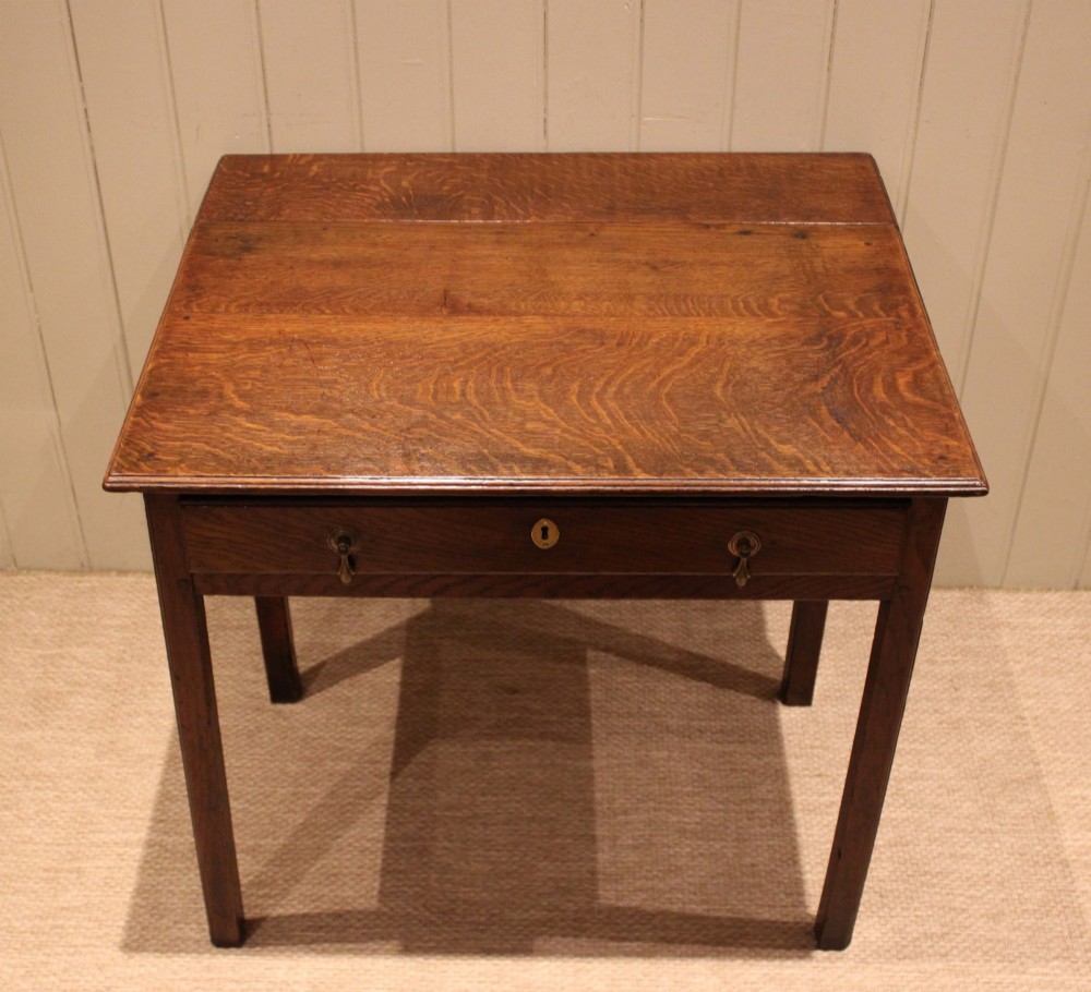 A George III oak side table with a frieze drawer, brass drop handles, a keyhole escutcheon, and straight square legs. View XI