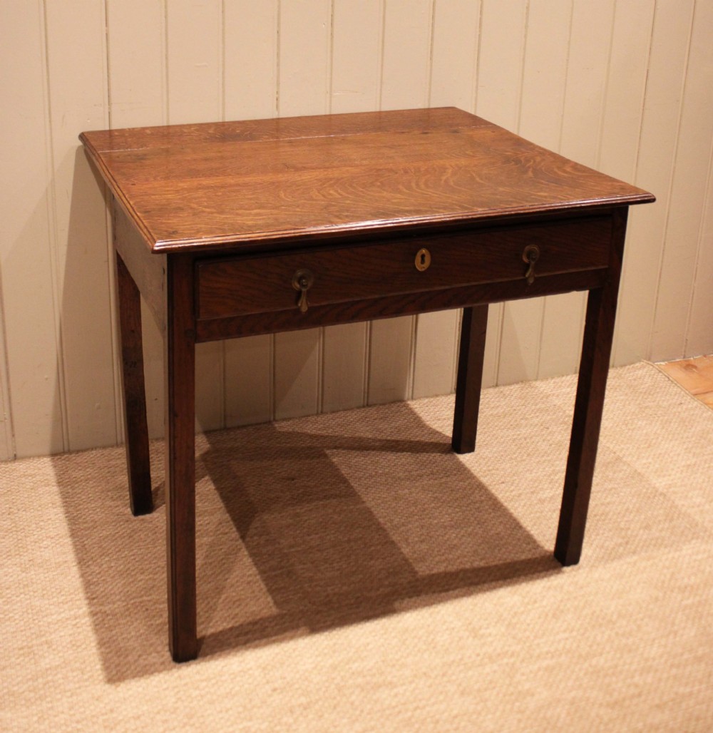 A George III oak side table with a frieze drawer, brass drop handles, a keyhole escutcheon, and straight square legs. View XIII