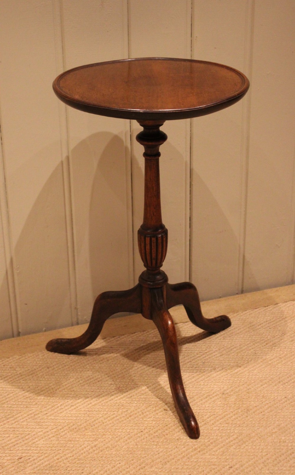 A mahogany wine table featuring a circular dished top supported by a turned reeded pedestal on three splayed cabriole legs. View V