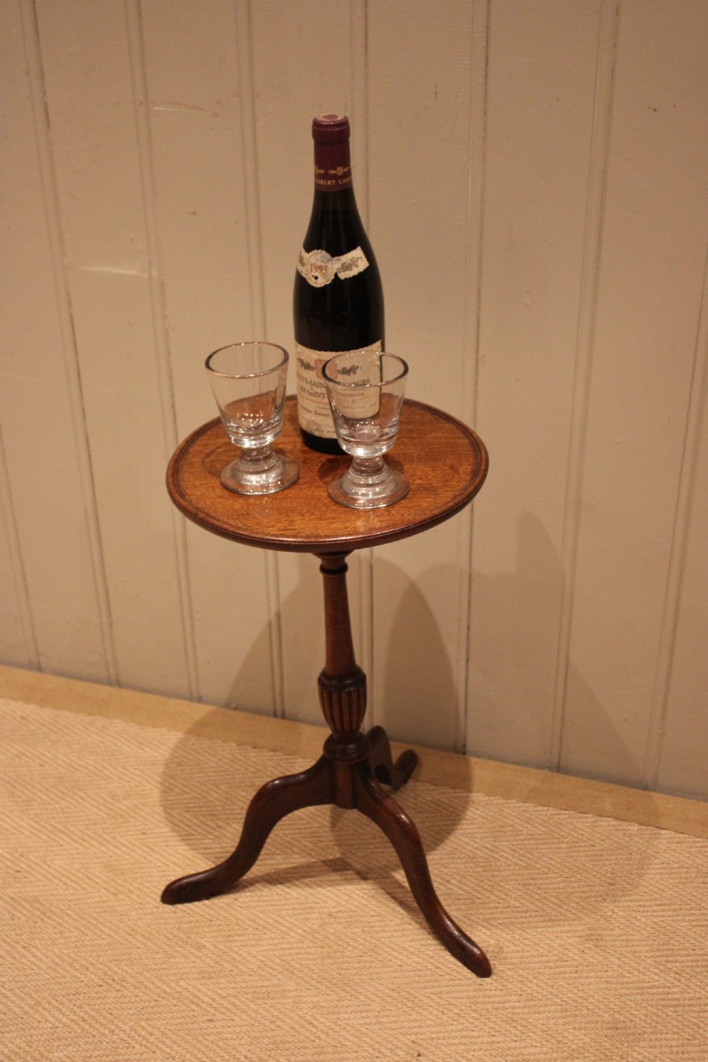 A mahogany wine table featuring a circular dished top supported by a turned reeded pedestal on three splayed cabriole legs. View X