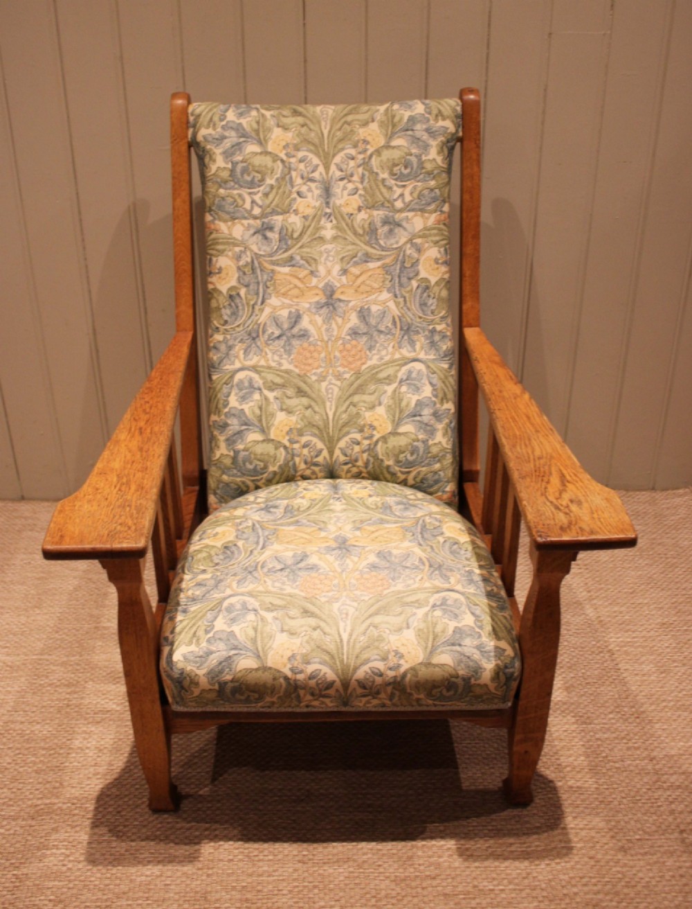 A solid oak Arts and Crafts style armchair featuring broad flat armrests and upholstery decorated with a botanical foliage pattern. View XIV