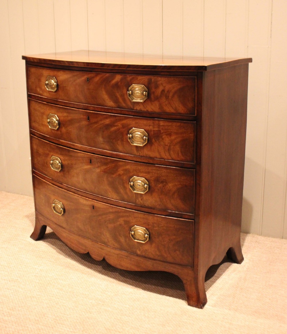 A Georgian flame mahogany bowfront chest of drawers featuring four graduated drawers with brass handles and splayed bracket feet.