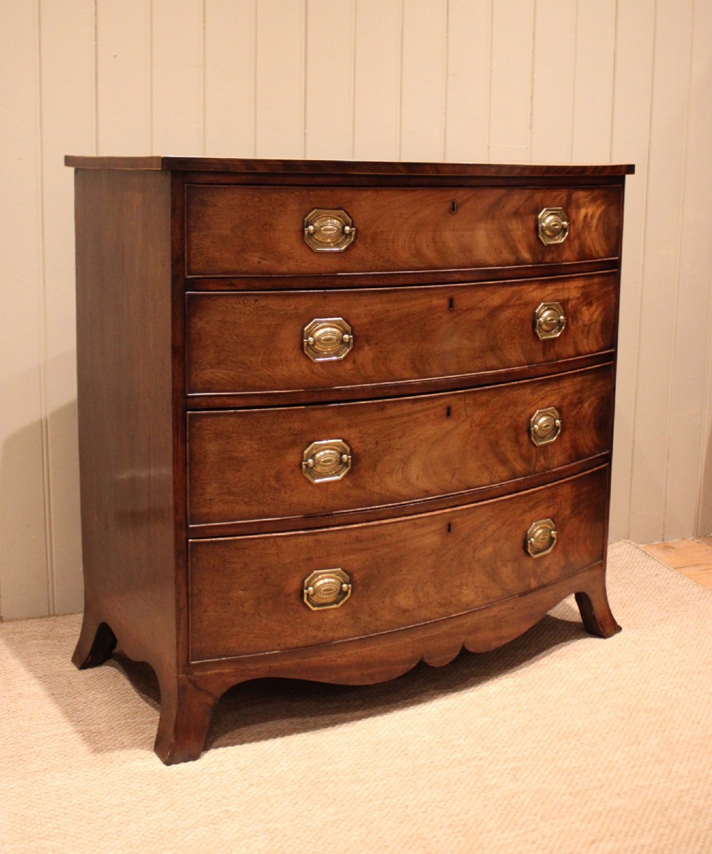 A Georgian flame mahogany bowfront chest of drawers featuring four graduated drawers with brass handles and splayed bracket feet. View III