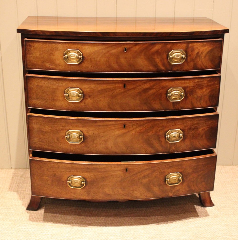 A Georgian flame mahogany bowfront chest of drawers featuring four graduated drawers with brass handles and splayed bracket feet. View IV