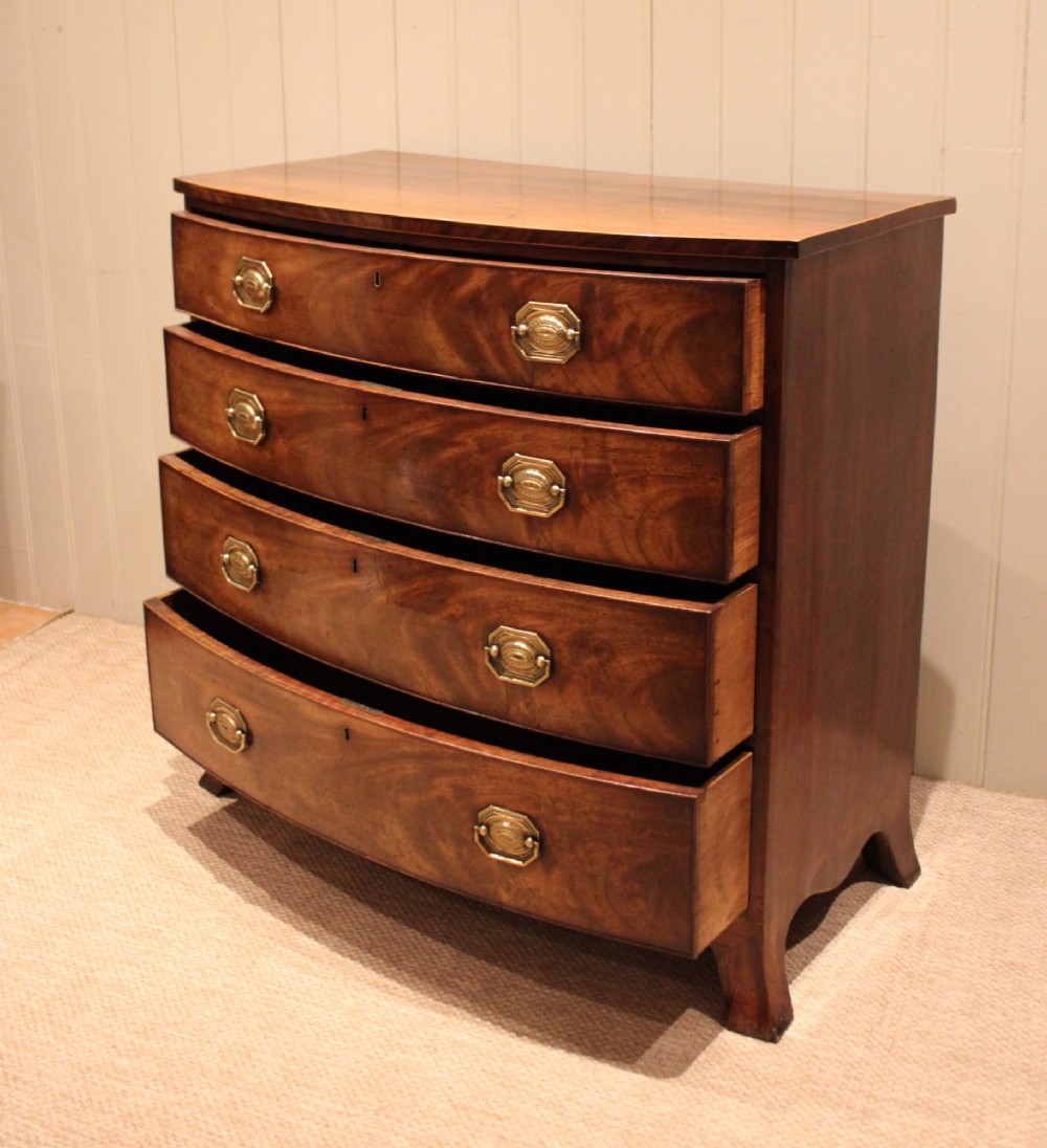A Georgian flame mahogany bowfront chest of drawers featuring four graduated drawers with brass handles and splayed bracket feet. View VII