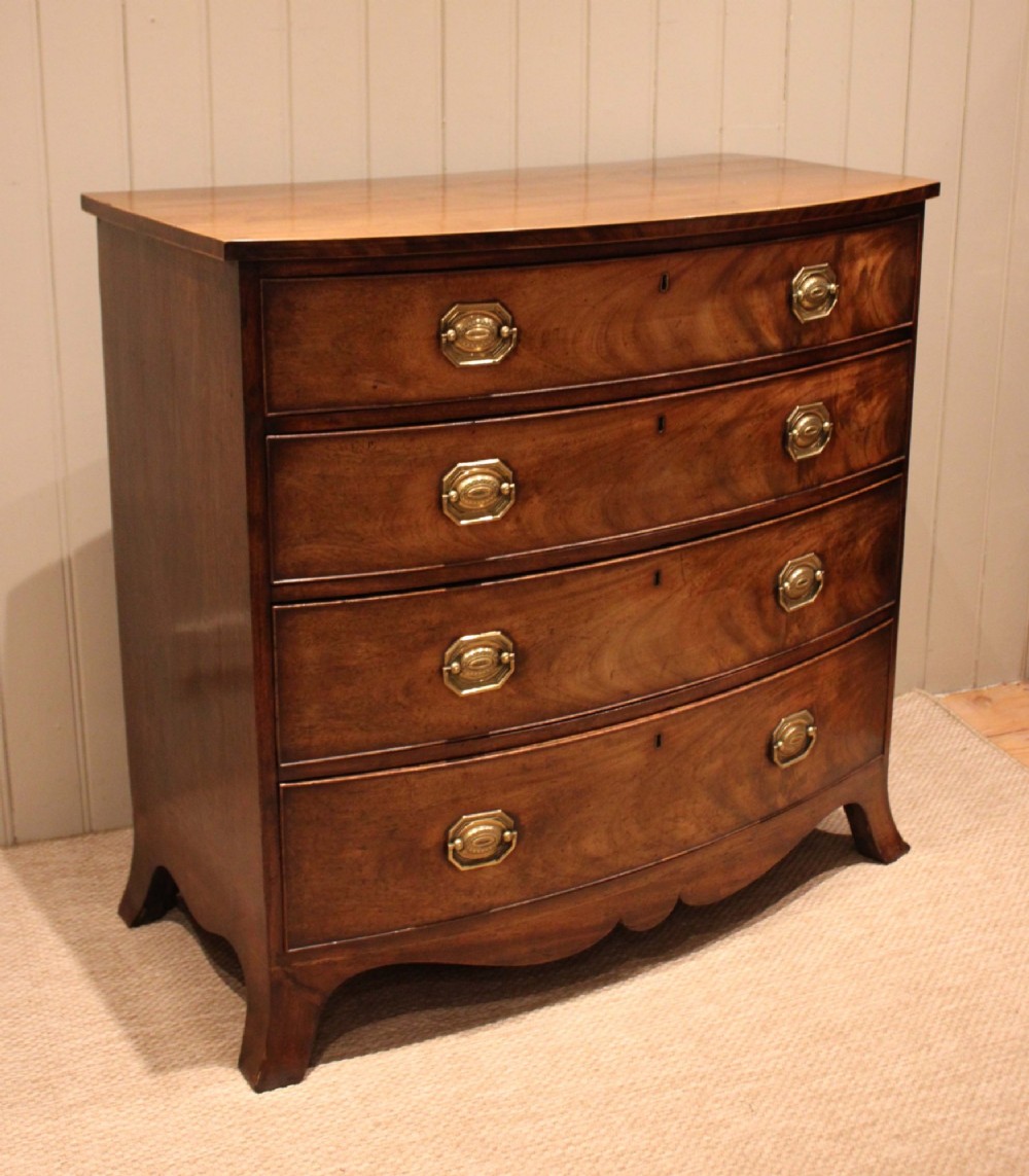 A Georgian flame mahogany bowfront chest of drawers featuring four graduated drawers with brass handles and splayed bracket feet. View VIII