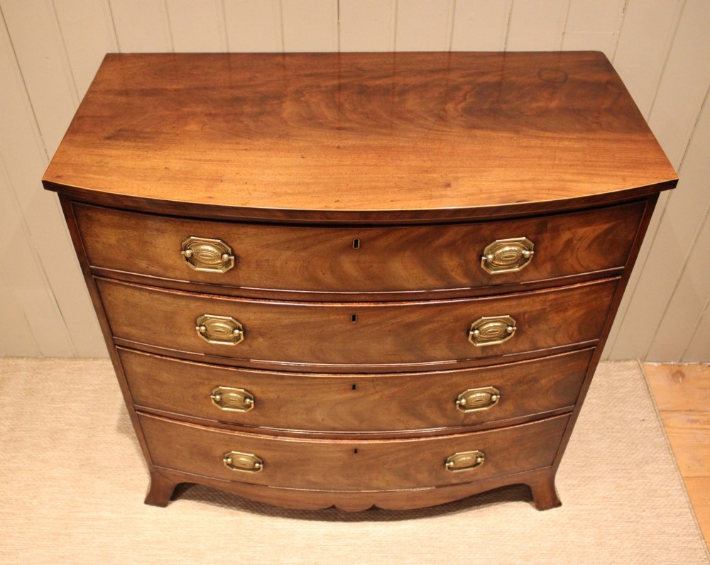 A Georgian flame mahogany bowfront chest of drawers featuring four graduated drawers with brass handles and splayed bracket feet. View XI