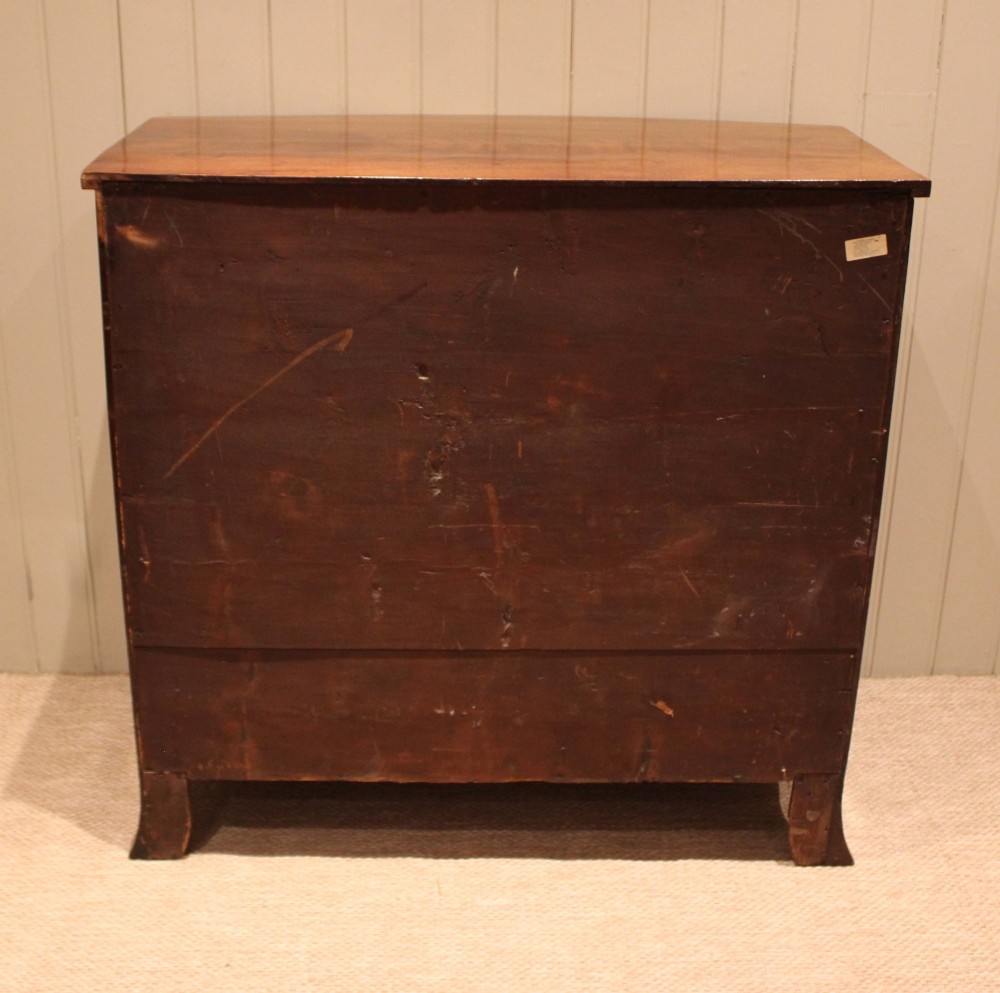 A Georgian flame mahogany bowfront chest of drawers featuring four graduated drawers with brass handles and splayed bracket feet. View XII