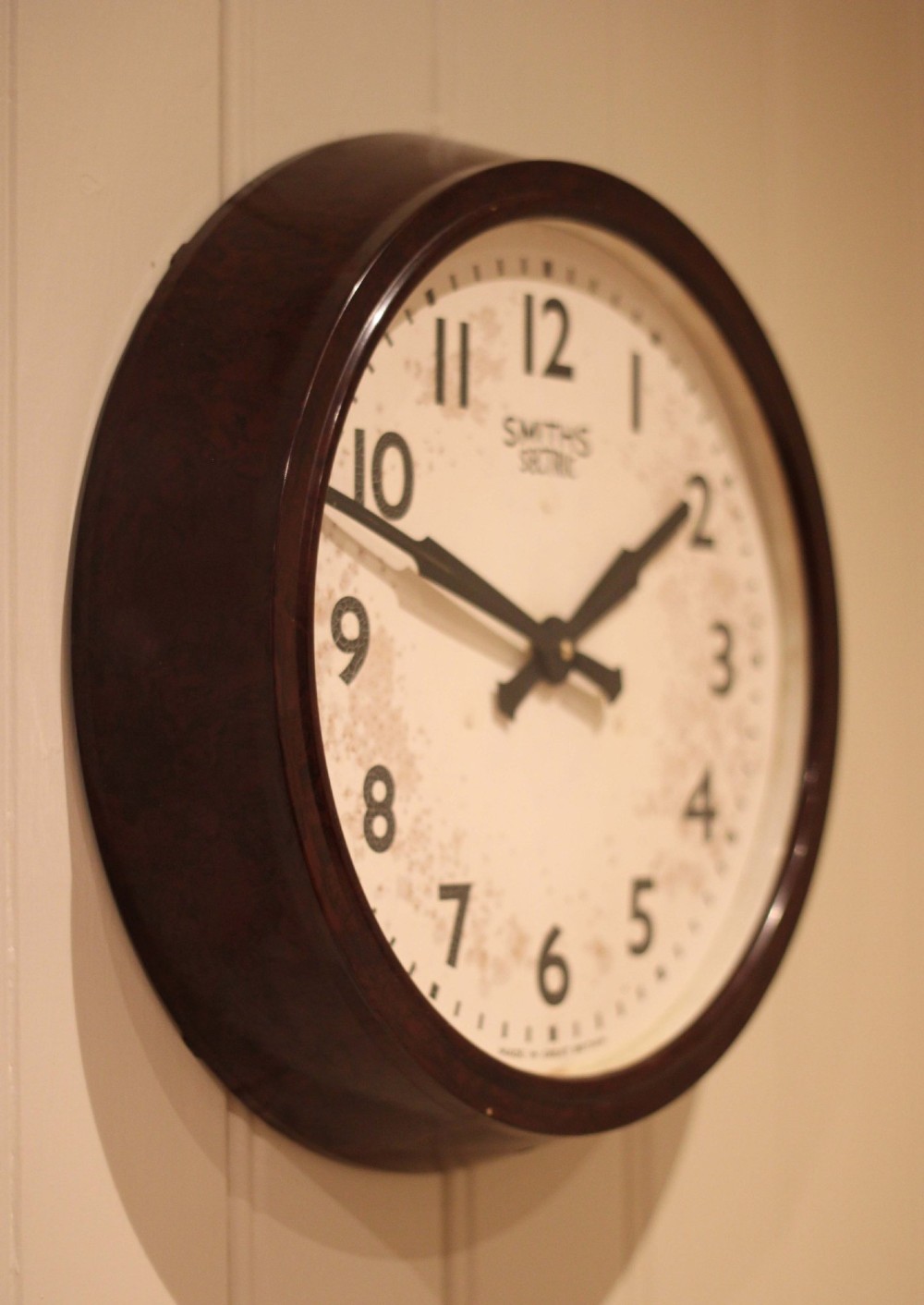 A circular vintage British Smiths Sectric wall clock featuring a dark brown Bakelite frame and an off-white dial with black Arabic numerals. View III