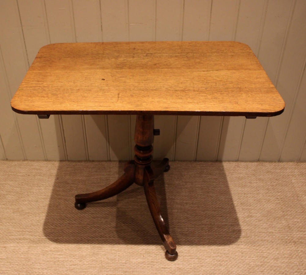 A late Georgian oak tilt-top table featuring a rectangular top with rounded corners, supported by a turned central column and a tripod base. View II