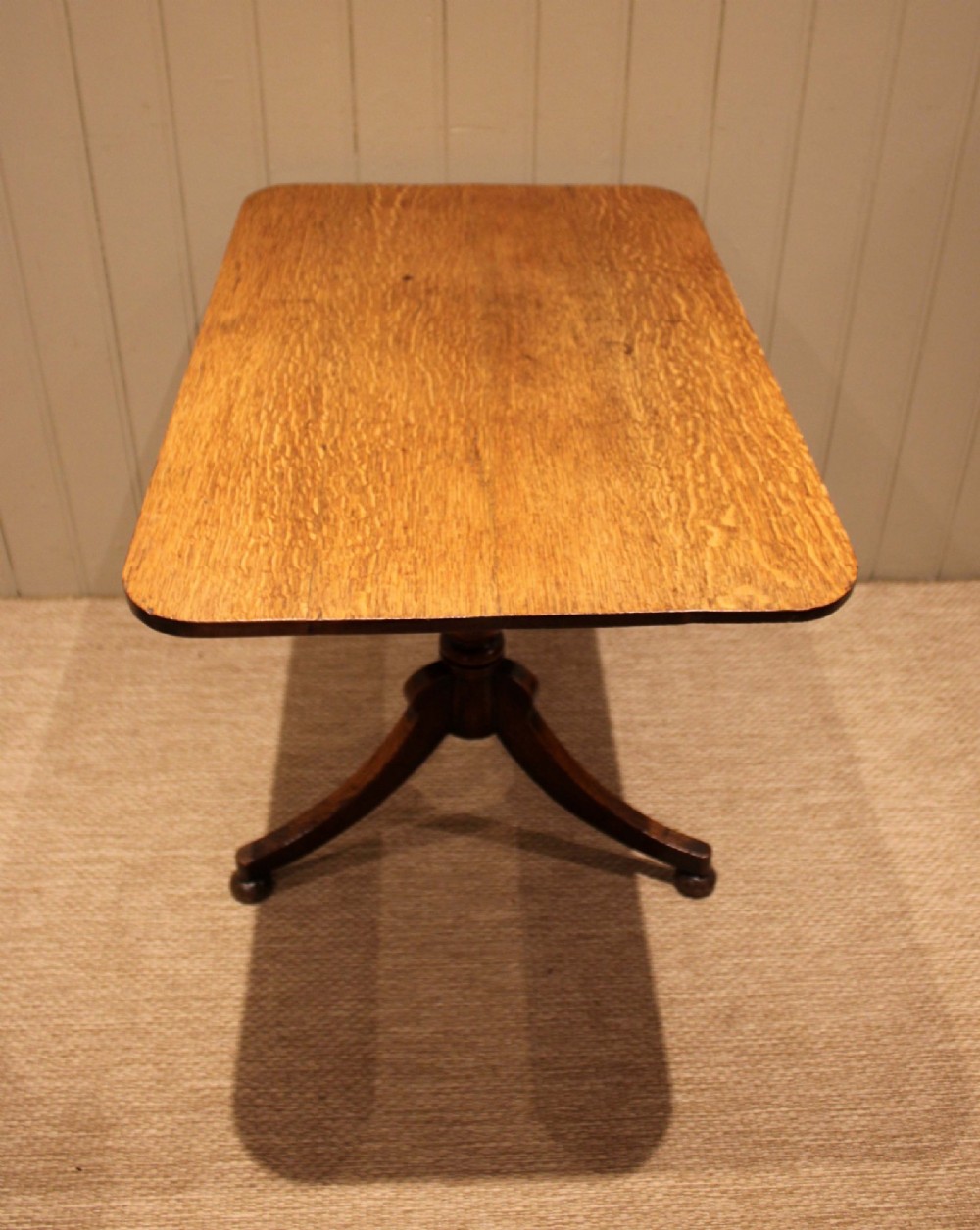A late Georgian oak tilt-top table featuring a rectangular top with rounded corners, supported by a turned central column and a tripod base. View IV