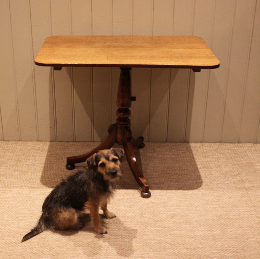 A late Georgian oak tilt-top table featuring a rectangular top with rounded corners, supported by a turned central column and a tripod base. View V