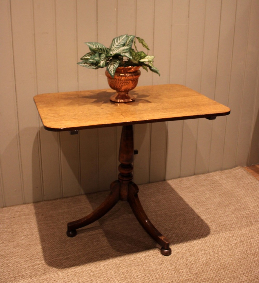 A late Georgian oak tilt-top table featuring a rectangular top with rounded corners, supported by a turned central column and a tripod base. View VI