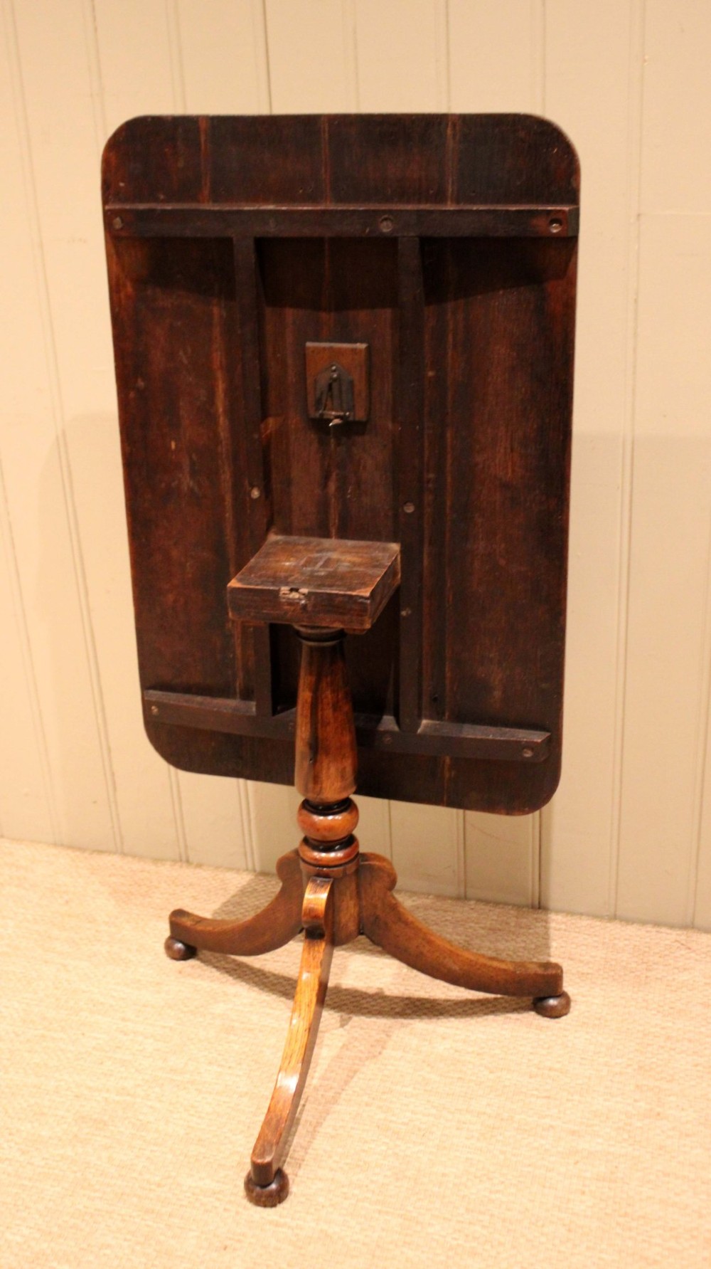 A late Georgian oak tilt-top table featuring a rectangular top with rounded corners, supported by a turned central column and a tripod base. View X